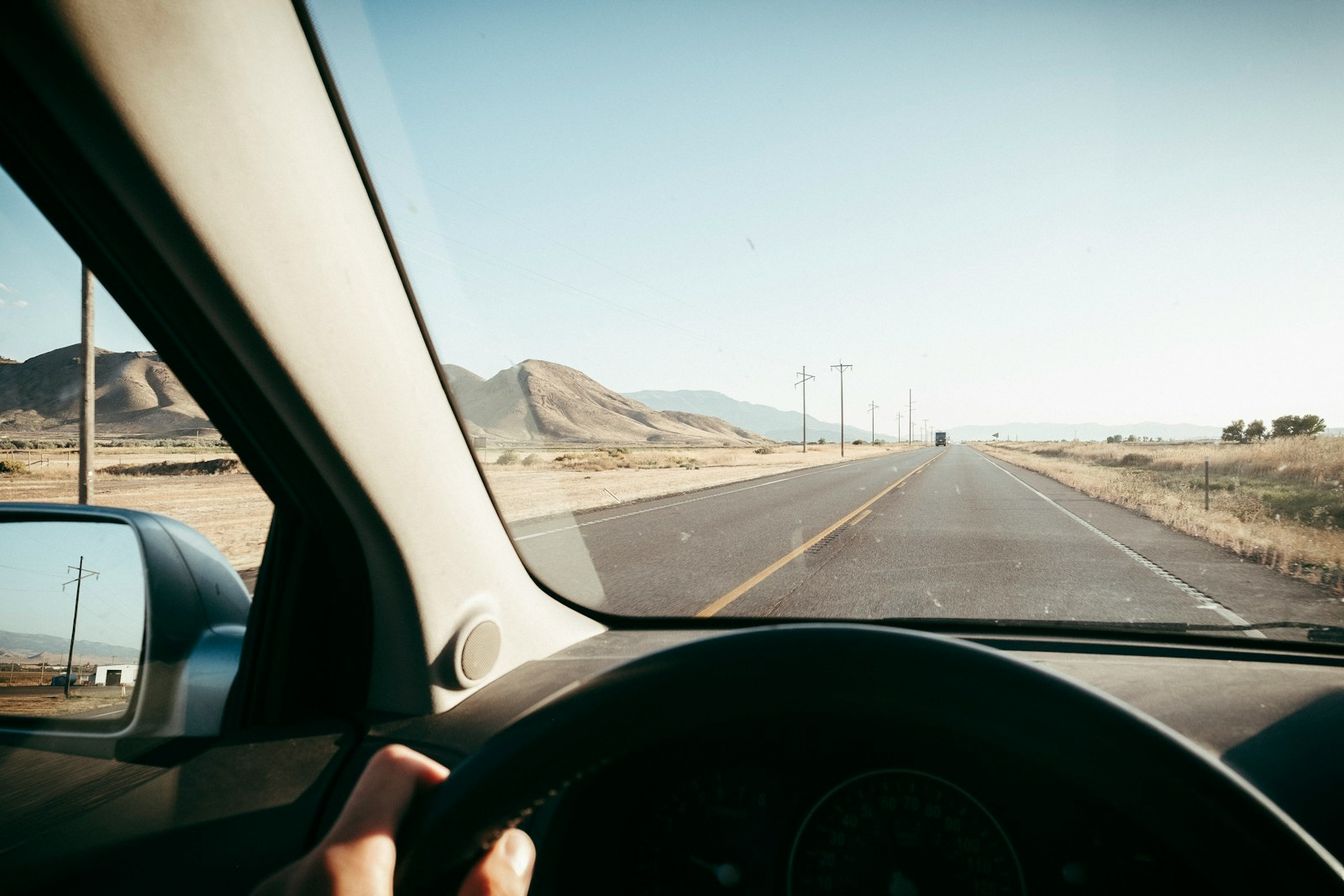 a person driving a car on a road with mountains in the background